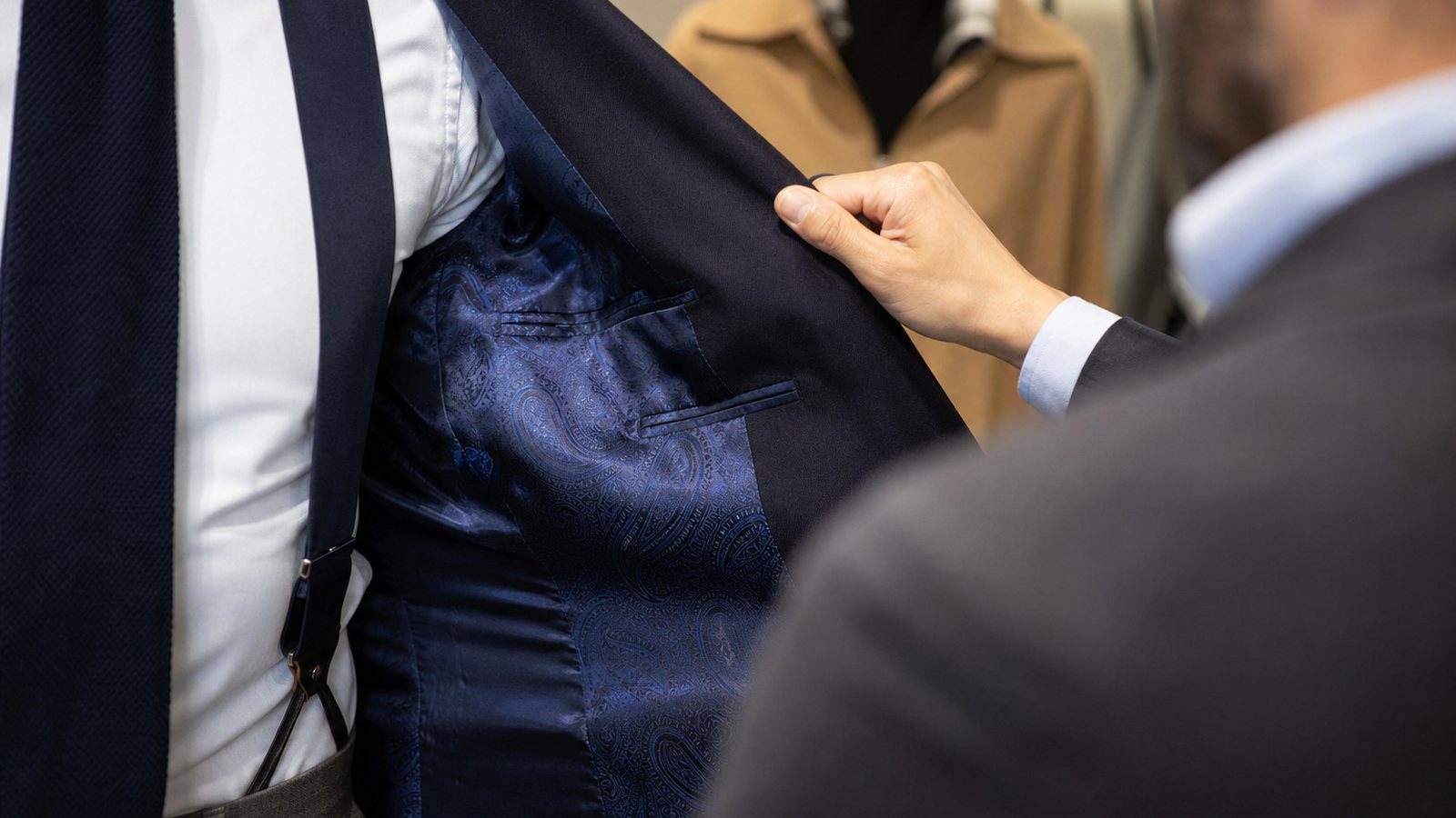 Gros plan sur la doublure, les boutons de corne et une boutonnière cousue main d'un costume sur mesure